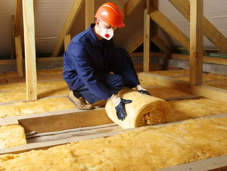 Contractor handling fiberglass insulation rolls during a home insulation installation