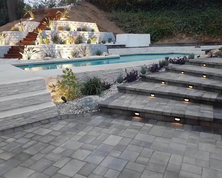 Tiered hardscape steps with landscape lighting installed in a residential backyard