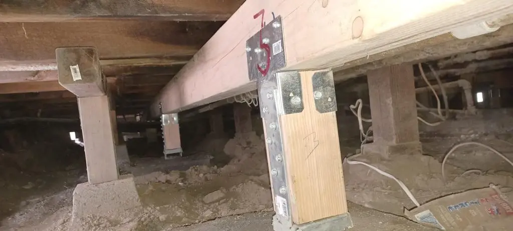 Crawl space foundation repair with steel post brackets and beam supports in a Southern California home
