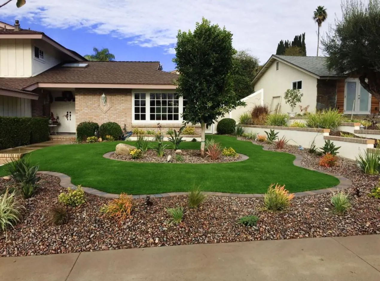 Professionally landscaped front yard with lawn, shrubs, and palm trees on a Southern California home