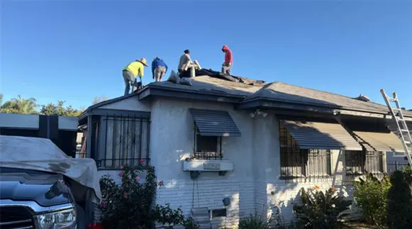 Roofing crew removing old shingles during a roof replacement on a Southern California home