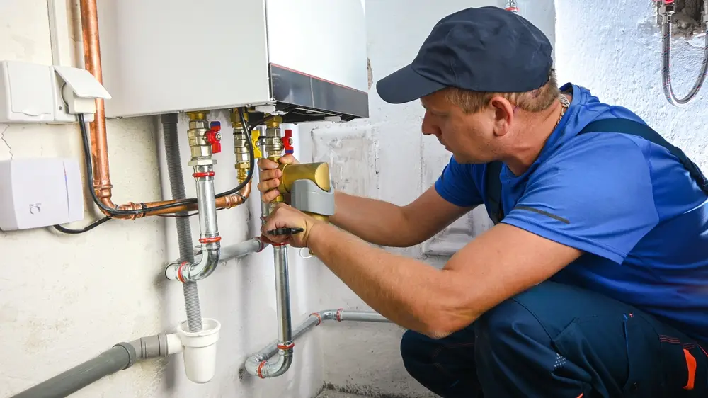 Plumber installing a tankless water heater and connecting water supply lines