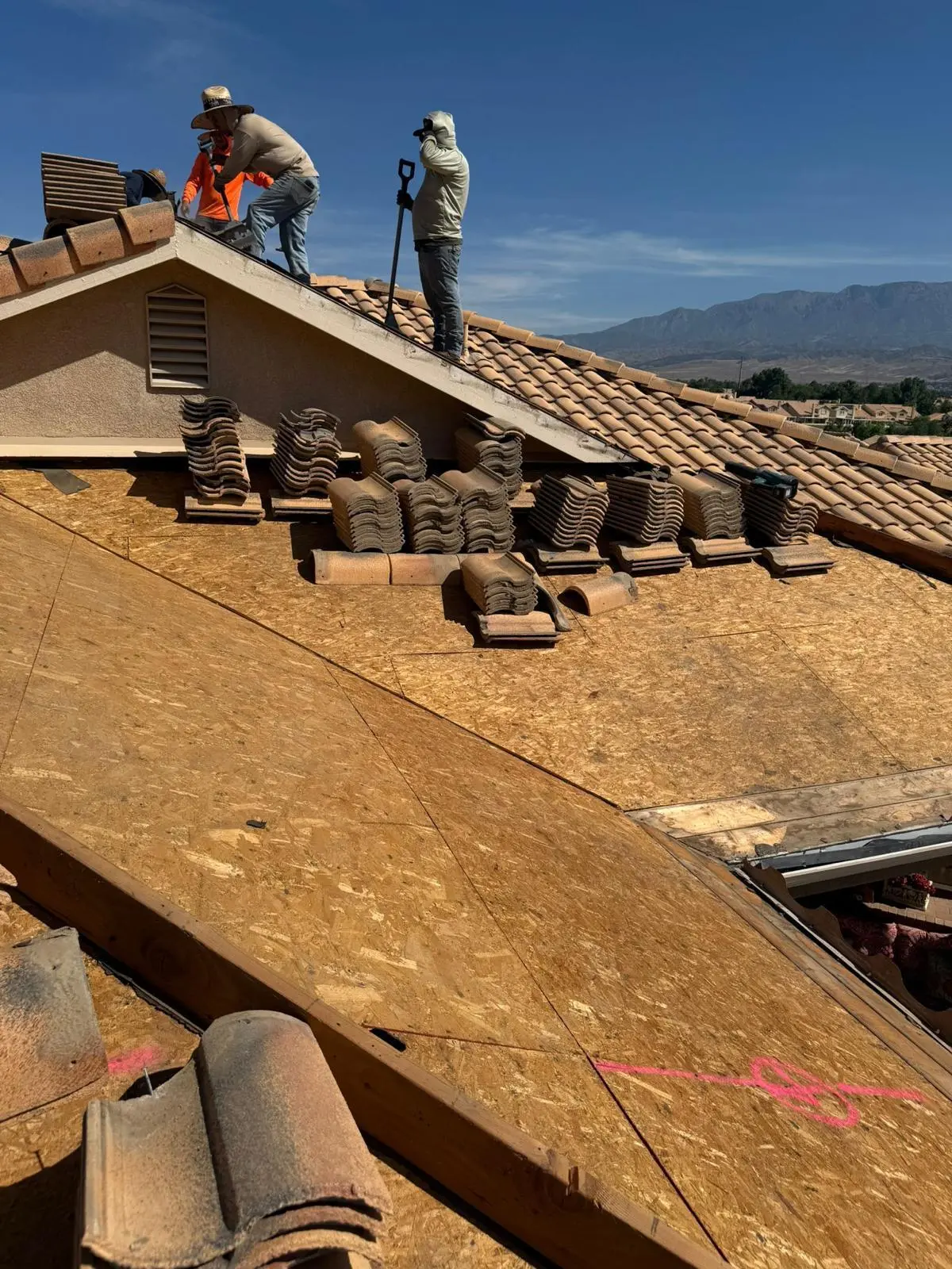 tile roof replacement in progress with new plywood decking laid and replacement tiles staged