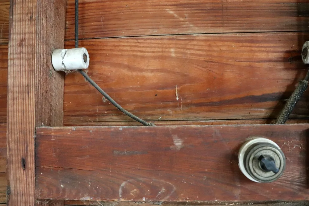 ceramic knob carrying a knob-and-tube conductor beside a period rotary light switch