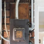 vintage fuse box on a brick wall with its original replace fuses plate and cloth-covered wiring